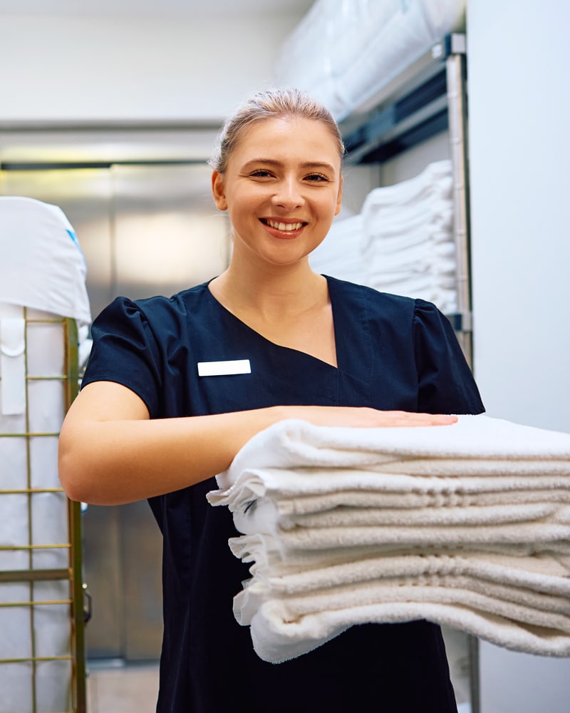 a housekeeper holds a stack of towels